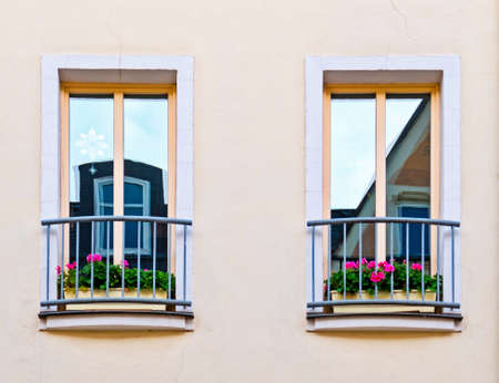 french style balcony window with geranium flower pots, house facade detailの写真素材