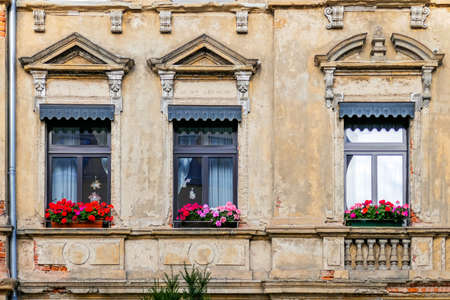 weathered but beautiful house windows with geranium flowersの写真素材