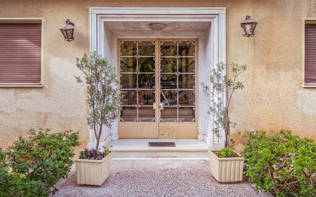 The front door of a house with a beautiful window and flower potsの写真素材