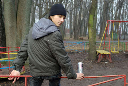 Boy sitting in playground drinking beerの写真素材