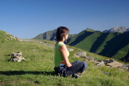 Woman sitting on grass in mountains relaxingの写真素材