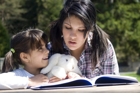 Teenage girl reads a story to little sister