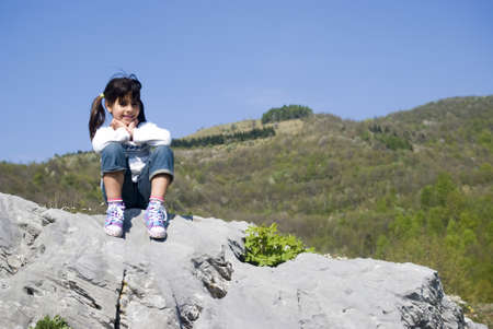 A girl sitting on a rockの写真素材