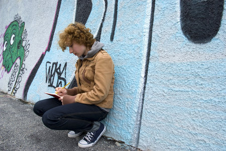 Girl sitting against a graffiti wall and writtenの写真素材
