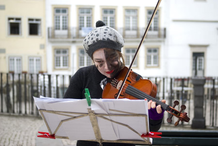 Coimbra, Portugal – November 25, 2010: Young female busker playing violin on the street 