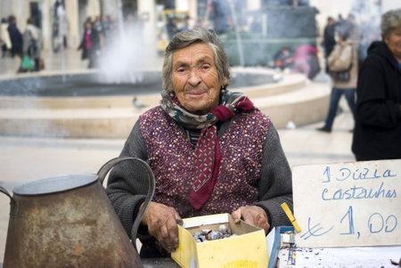 Coimbra, Portugal  November 25, 2010: Poor elderly woman sells chestnuts on the street of cityのeditorial素材