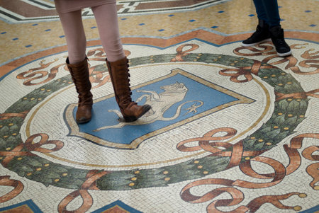 Milan, Italy - March 8, 2016: Mosaic floor of Vittorio Emanuele gallery in Milan. Tourist using the heel of his shoe to spinning on the genitals of the Bull for good luck. The tradition said that - if a person spins around three times with a heel on the tのeditorial素材