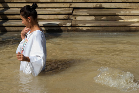 Qasr el Yahud, Israel - October 29, 2016: A woman immerses Themselves into the waters of the Jordan River baptismal site of Qasr el Yahud in Israel. The baptismal site on the banks of the Jordan River, is the site where according to Functional tradition, のeditorial素材