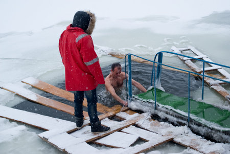 Khmelnytskyi, Ukraine - January 19, 2012: Man plunge in icy water in the Southern Bug River to celebrate the Epiphany religious holiday. Orthodox feast of Baptism is celebrated annually on 19 January. To Orthodox believers, water blessed by a priest on Epのeditorial素材