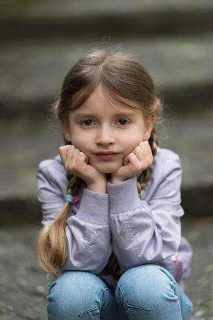 Little girl sitting on the stairs on rainy day