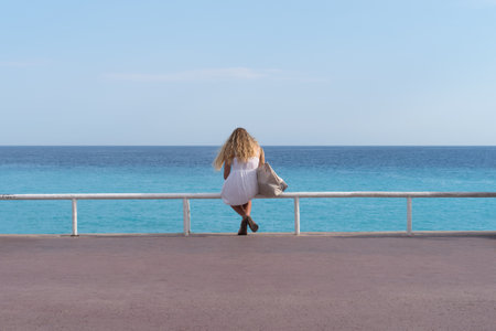 Nice, France - July 15, 2017: A young woman sits in front on the Promenade des Anglais seafrontのeditorial素材