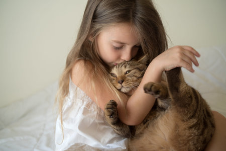 Child playing with cat on bedの写真素材