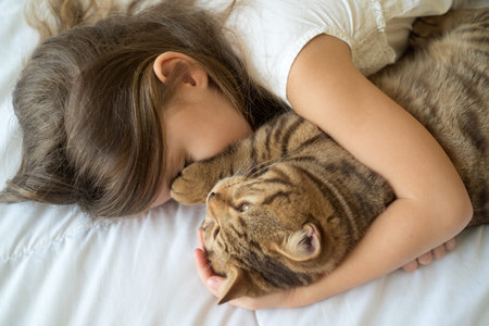Cat lying on bed with young girlの写真素材