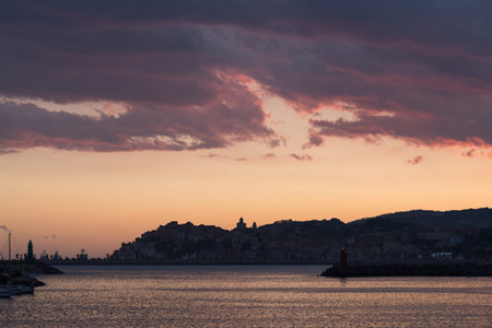 Dramatic colorful clouds at sunset with cityscape silhouette. Imperia, Italyの写真素材