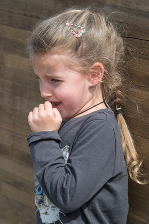 Little girl cry beside wooden wall