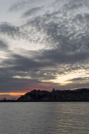 Dramatic colorful clouds at sunset with cityscape silhouette - Imperia, Liguria, Italyの写真素材
