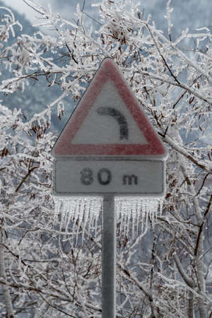 Road sign danger curve covered in ice after the freezing rainの写真素材