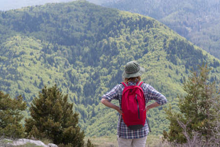 Woman hiker stands and enjoys valley view の写真素材