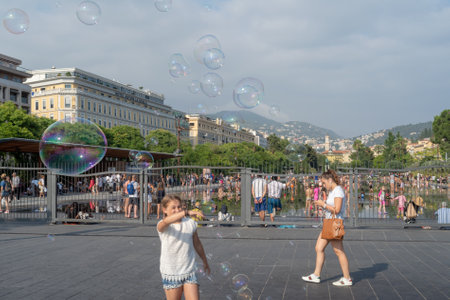Nice, France - July 4, 2018: Lovely new fountain in the heart of Nice, (Promenade du Paillon). Many kids are getting excited at water springing up at the fountain surrounded by beautiful historic buildings and green urban park 1,2 km longのeditorial素材