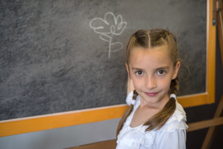 Elementary school student girl posing at the  blackboard