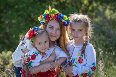 Mother and daughters in traditional Ukrainian costumes posing in the spring countrysideの写真素材
