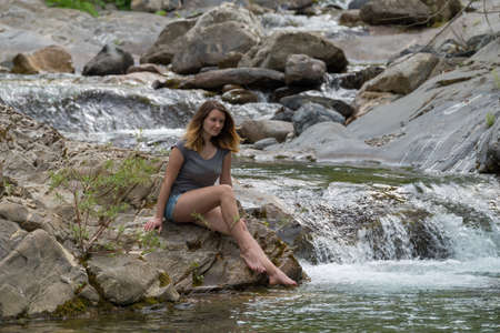 Young woman enjoying the pure waters of a mountain riverの写真素材