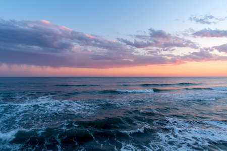 Dramatic colorful clouds at sunset hovering over the seaの写真素材