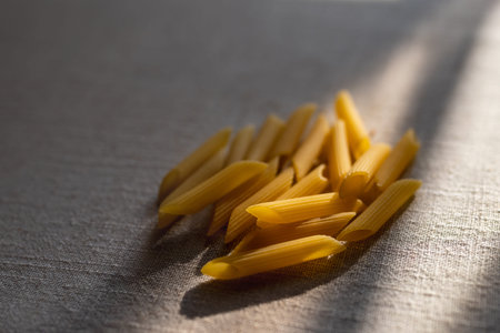 Uncooked penne pasta on table 