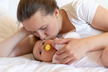 Mother and baby girl relaxing at home lying in bed together