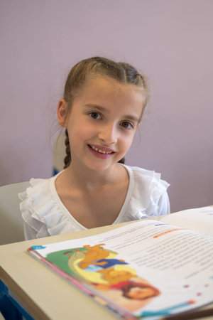 Pretty elementary school girl working on assignment in classroom