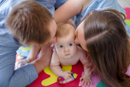 Mother and father together with their daughter on colorful puzzle play mat