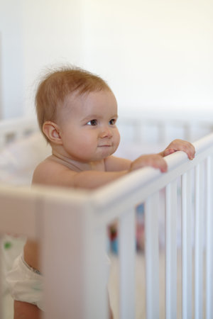 8 month old baby girl standing in the crib