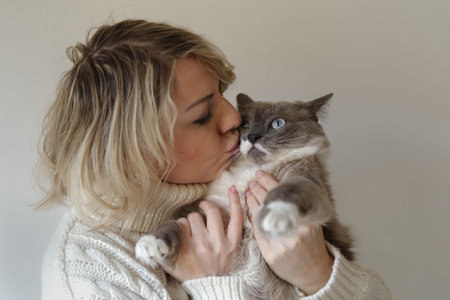 Close up of a woman hugging her Siamese cat indoor