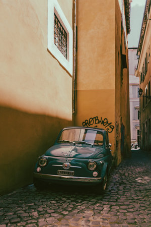 Rome, Italy - June 12, 2021: Fiat 500 classic car parked in a narrow ancient alley in the historic...