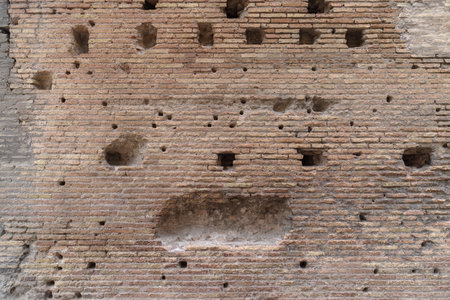 Weathered ancient Roman brick wall revealing aged surface, eroded details, historical architectural texture, Colosseum, Rome, Italyの写真素材
