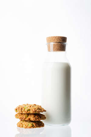Bottle with milk on a white background. Glass bottle. Natural cork. White drink. Cows milk. Homemade cookies on a white background. Pyramid of cookies. Cookies on top of each other.の写真素材