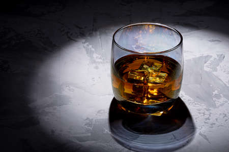 Glass of whiskey with ice on a black background. Concrete background. Marble countertop. Concrete worktop. Whiskey / Brandy / Cognac / Rum. Glass with a strong drink.の写真素材