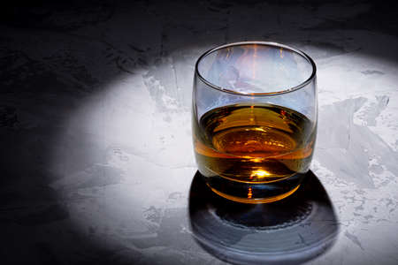 Glass of whiskey with ice on a black background. Concrete background. Marble countertop. Concrete worktop. Whiskey / Brandy / Cognac / Rum. Glass with a strong drink.の写真素材