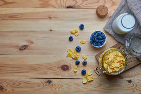 Cornflakes with milk for breakfast. Blueberries. Milk in a glass bottle. Linen napkin. Wood background. View from above. Flat lay.の写真素材