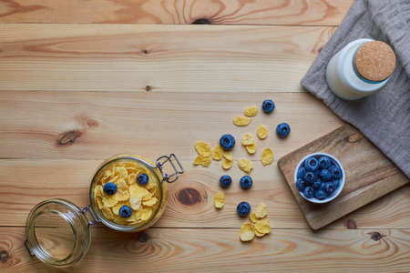 Cornflakes with milk for breakfast. Blueberries. Milk in a glass bottle. Linen napkin. Wood background. View from above. Flat lay.の写真素材