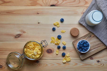 Cornflakes with milk for breakfast. Blueberries. Milk in a glass bottle. Linen napkin. Wood background. View from above. Flat lay.の写真素材