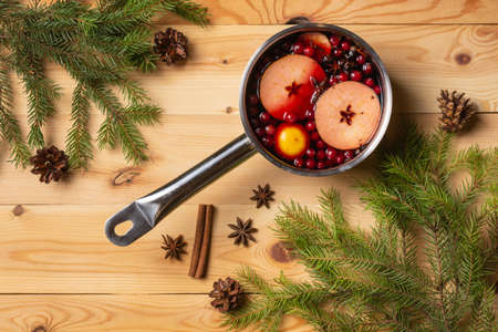 Pan with cranberry-apple mulled wine. Woody background. Fir branches. View from above.の写真素材