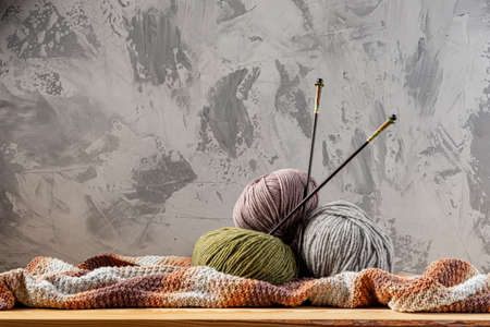 Skeins of yarn for knitting from natural wool on a wooden surface or table. Background - concrete wall. Wooden knitting needles.の写真素材