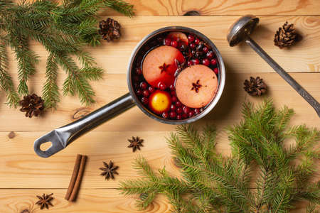 Pan with cranberry-apple mulled wine. Woody background. Fir branches. View from above.の写真素材