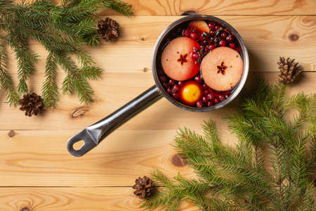 Pan with cranberry-apple mulled wine. Woody background. Fir branches. View from above.の写真素材
