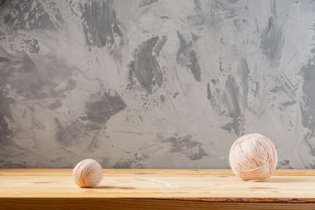 Skeins of yarn for knitting from natural wool on a wooden surface or table. Background - concrete wall. Wooden knitting needles.の写真素材