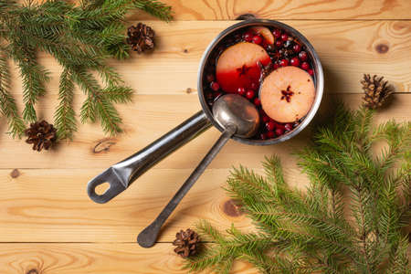 Pan with cranberry-apple mulled wine. Woody background. Fir branches. View from above.の写真素材