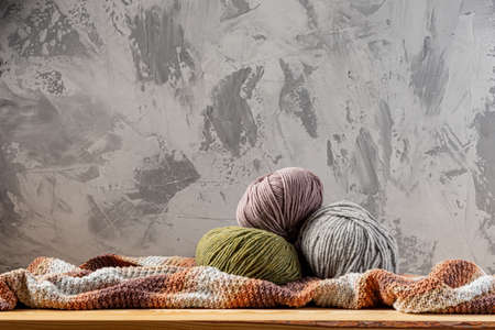 Skeins of yarn for knitting from natural wool on a wooden surface or table. Background - concrete wall. Wooden knitting needles.の写真素材