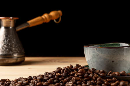 Handmade cup with coffee on the table. Countertop made of wood. Coffee beans. Black background.の写真素材