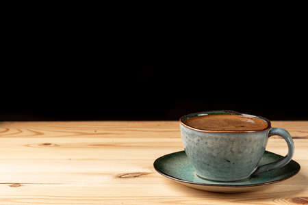 Handmade cup with coffee on the table. Countertop made of wood. Coffee beans. Black background.の写真素材